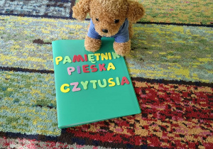 Piesek siedzi z książką na dywanie