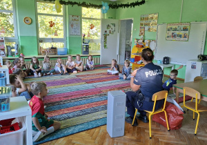 Dzieci biorą udział w zajęciach z przedstawicielami policji. Przypominają sobie zasady bezpieczeństwa na drodze