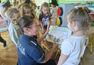 Dzieci biorą udział w zajęciach z przedstawicielami policji. Przypominają sobie zasady bezpieczeństwa na drodze