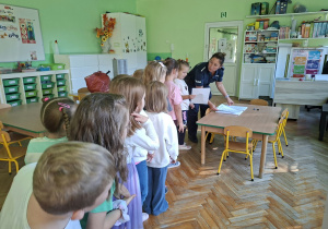 Dzieci biorą udział w zajęciach z przedstawicielami policji. Przypominają sobie zasady bezpieczeństwa na drodze