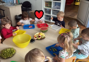 Dzieci kroją owoce na sałatkę owocową.