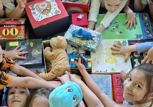 Dzieci siedzą na dywanie i oglądają zawartość swoich pudełek złości
