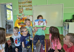 Dzieci siedzą na dywanie i oglądają zawartość swoich pudełek złości