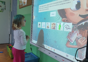 Dziecko stoi przed tablica multimedialna
