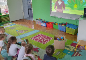 dzieci na dywanie oglądają film
