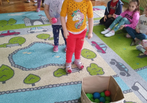dziewczynka wrzuca piłki do pudełka